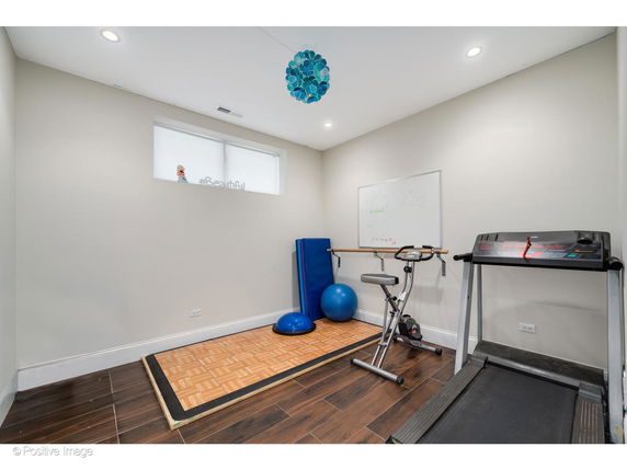Room with exercise equipment including a treadmill, exercise bike, and exercise mats.