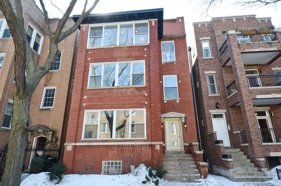 Front view of a three-story brick building with multiple windows.