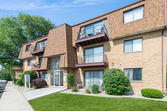 Front view of a multi-story brick apartment building with balconies.