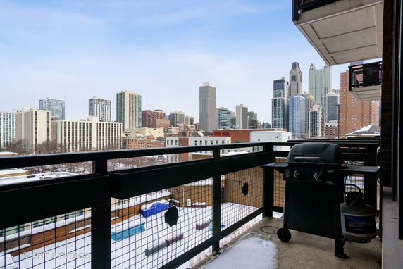 Panoramic view of city skyline from a balcony with a grill.