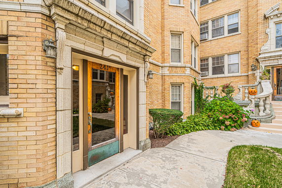 Front view of a multi-story brick building entrance with decorative elements and a pathway.