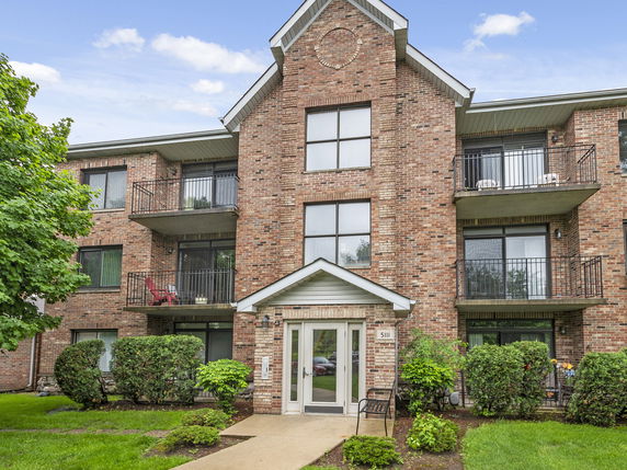 Front view of a multi-story brick apartment building with balconies.