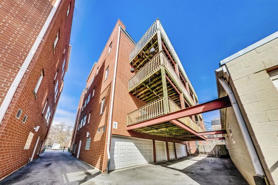 View of a brick apartment building with multiple balconies and garage doors below.