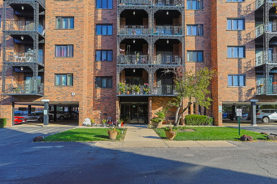 Front view of a multi-story apartment building with brick facade and balconies.