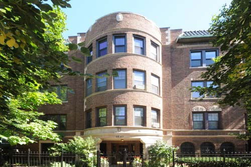 Front view of a multi-story brick building with rounded central section and multiple windows.