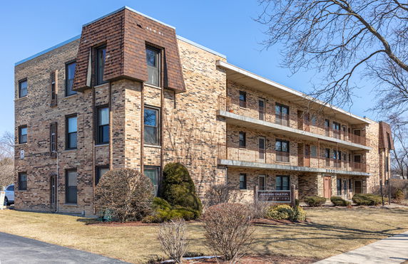 Front view of a multi-story brick apartment building with balconies.