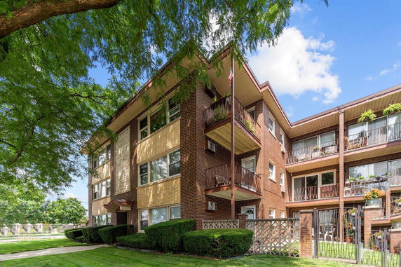 Front view of a multi-story brick apartment building with balconies.