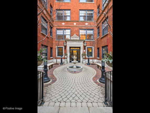 Front view of a brick building with a decorative entrance and pathway.