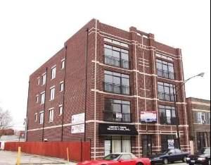Front view of a four-story brick building with large windows.
