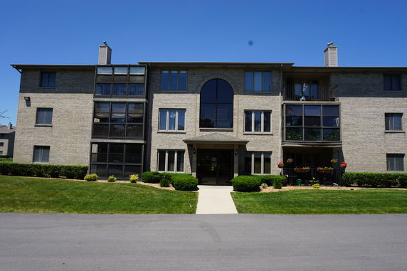 Front view of a three-story residential building with brick facade and multiple windows.