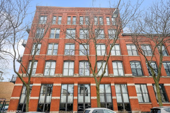Front view of a multi-story brick building with large windows.