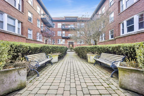 Front view of a multi-story brick building with balconies and a courtyard path.