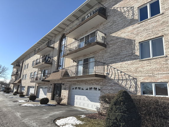 Front view of a multi-story apartment building with balconies and garages.