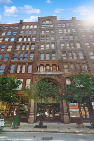 Front view of a multi-story brick building with arched entryway.
