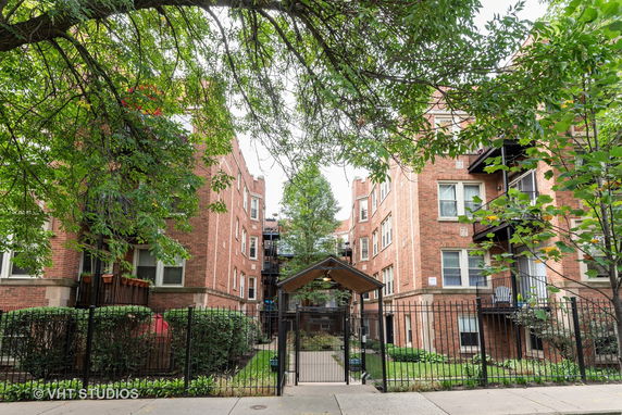 Front view of a brick apartment building with gated entrance.