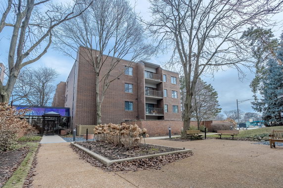 Front view of a four-story brick apartment building with balconies.