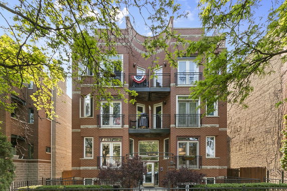 Front view of a brick, multi-story residential building with balconies.