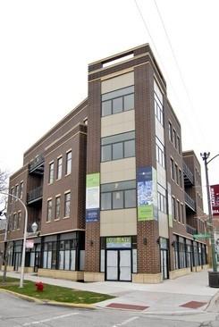 Front view of a multi-story brick building with commercial spaces on the ground floor.