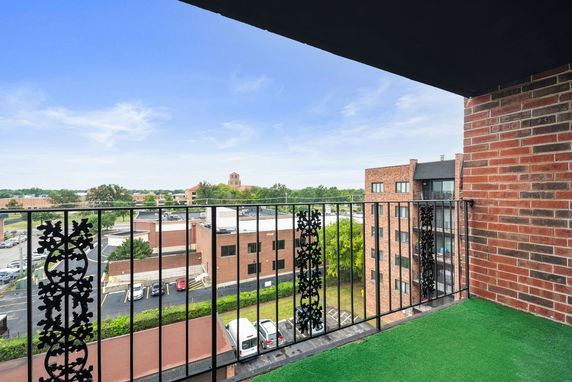 Panoramic view with buildings seen from a balcony with a green artificial turf floor.