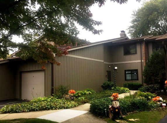 Front view of a two-story house with a garage and landscaped garden.