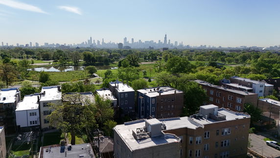 Panoramic view of a cityscape with multiple buildings and green park areas.