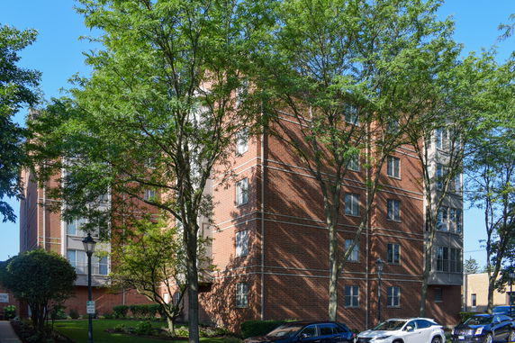 Front view of a multi-story brick building with trees in front.