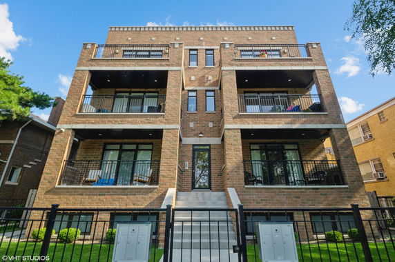 Front view of a three-story brick apartment building with balconies and central entrance.