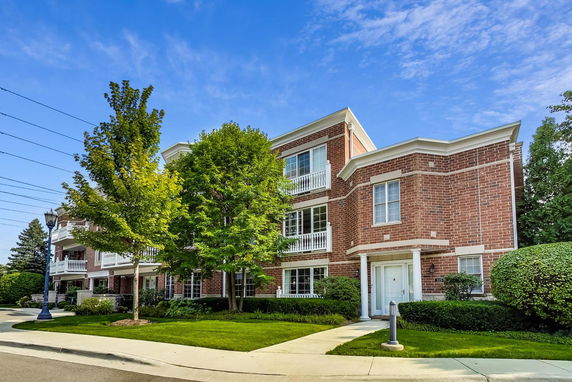 Front view of a three-story brick residential building with multiple balconies.
