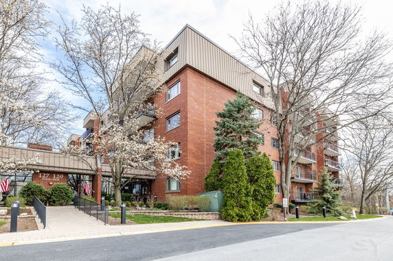 Front view of a multi-story brick apartment building with balconies.
