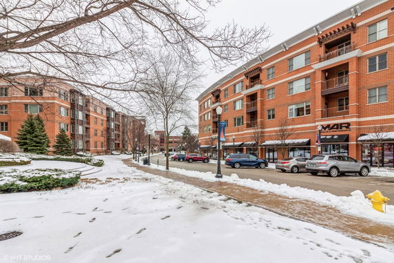 Front view of a multi-story brick building with parked cars and snow-covered ground.