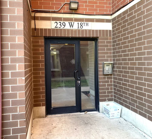Entrance view of a brick building with a glass door and address displayed above.