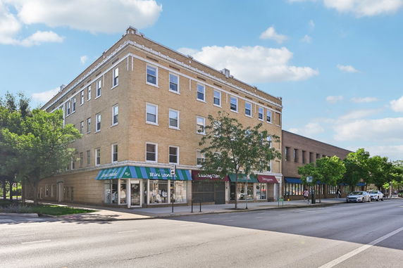 Front view of a multi-story commercial building with brick exterior and awnings over the storefronts.