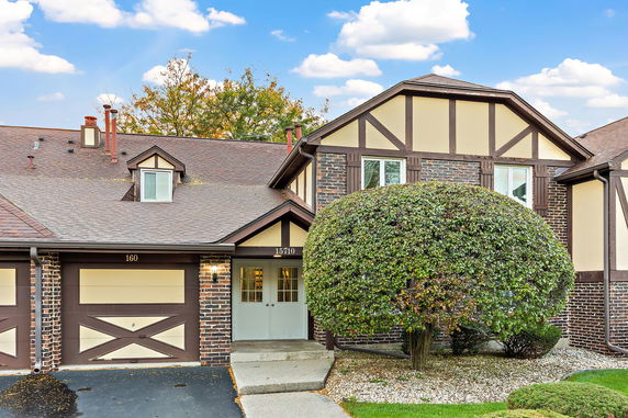Front view of a house with a Tudor-style exterior, featuring a garage and decorative wooden trim.