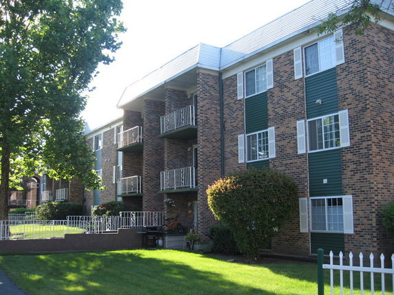 Front view of a multi-story brick apartment building with balconies.