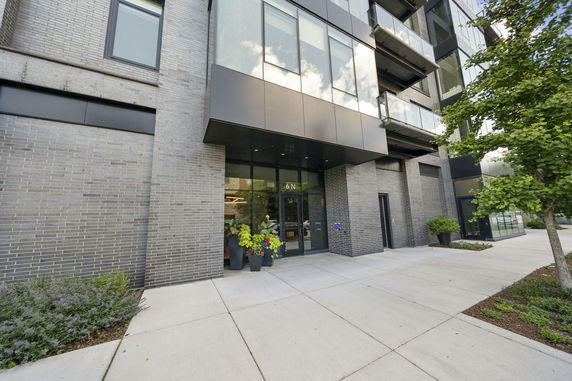 Front view of a modern building entrance with large windows and concrete pathway.