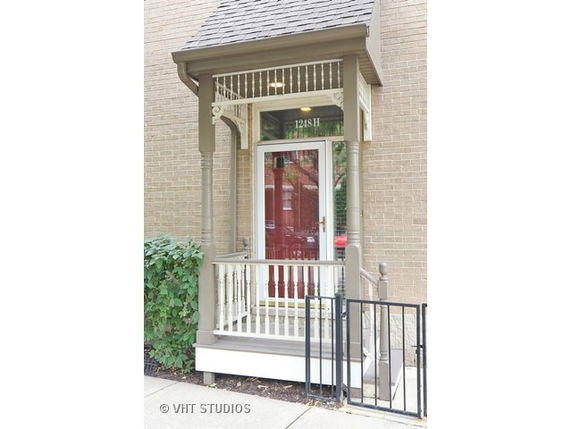 Front view of a building entrance with a small porch and decorative columns.