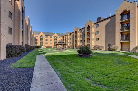 Front view of multi-story apartment buildings surrounding a green courtyard.