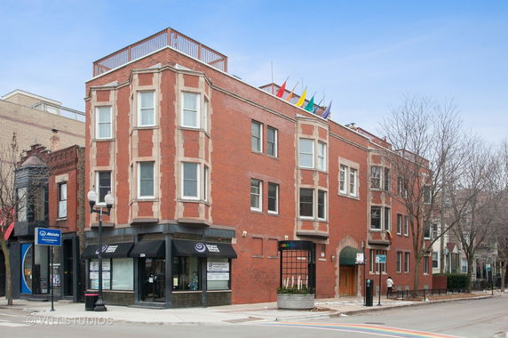 Front view of a multi-story brick building with large windows and a corner entrance.