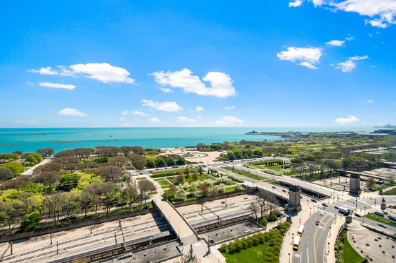 Panoramic view of a coastal landscape with roads, trees, and distant water.