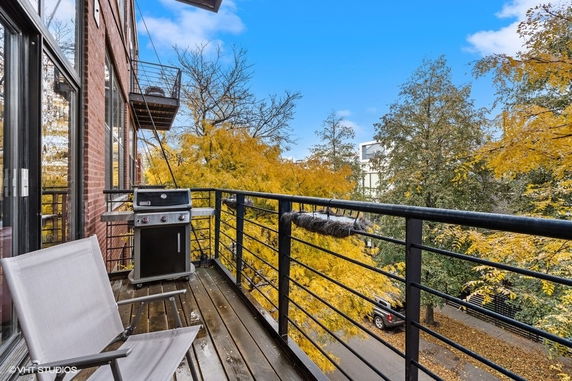 View from a balcony with railings overlooking trees and a street.