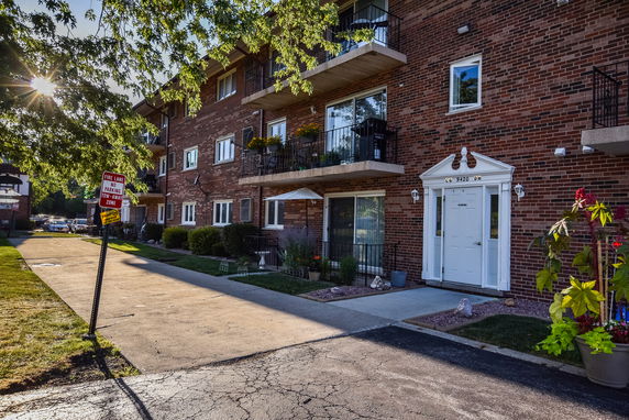 Front view of a brick apartment building with balconies and a white entrance door.