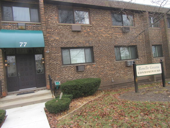 Front view of a brick condominium building with a green awning above the entrance.