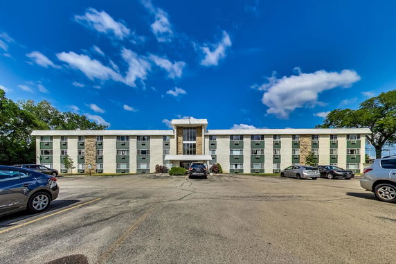 Front view of a three-story building with parking area.