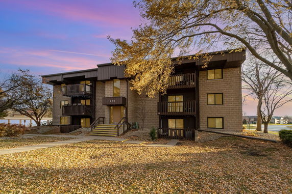 Front view of a multi-story building with balconies and stairs leading to the entrance.