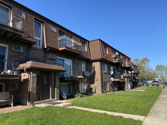 Front view of a multi-story brick apartment building with balconies.