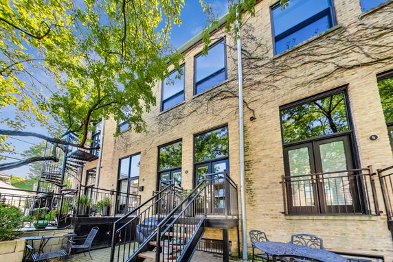 Front view of a multi-story brick building with large windows and metal railings.