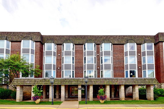 Front view of a three-story building with large windows and a covered entrance.