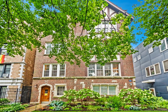 Front view of a multi-story brick building with a wooden door and multiple windows.