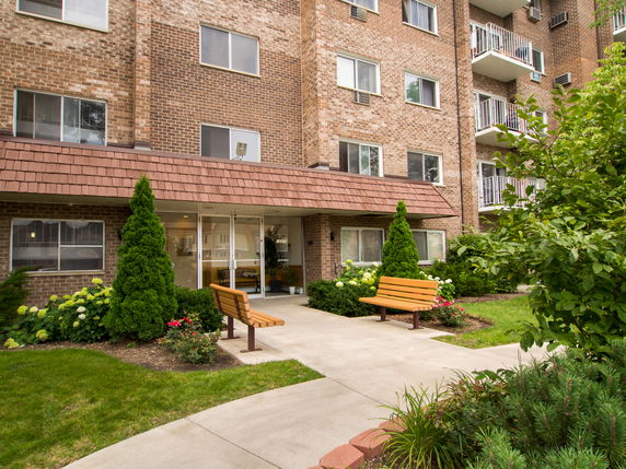 Front view of a multi-story brick apartment building with balconies.