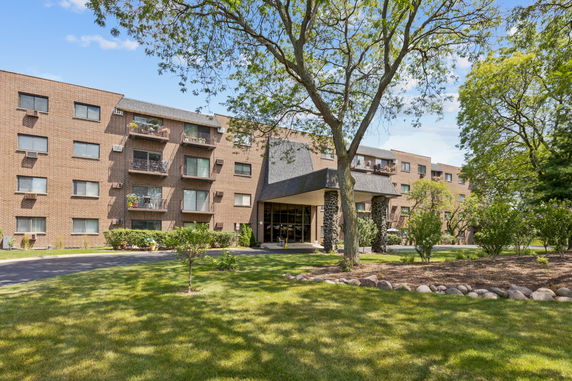 Front view of a multi-story brick apartment building with balconies.